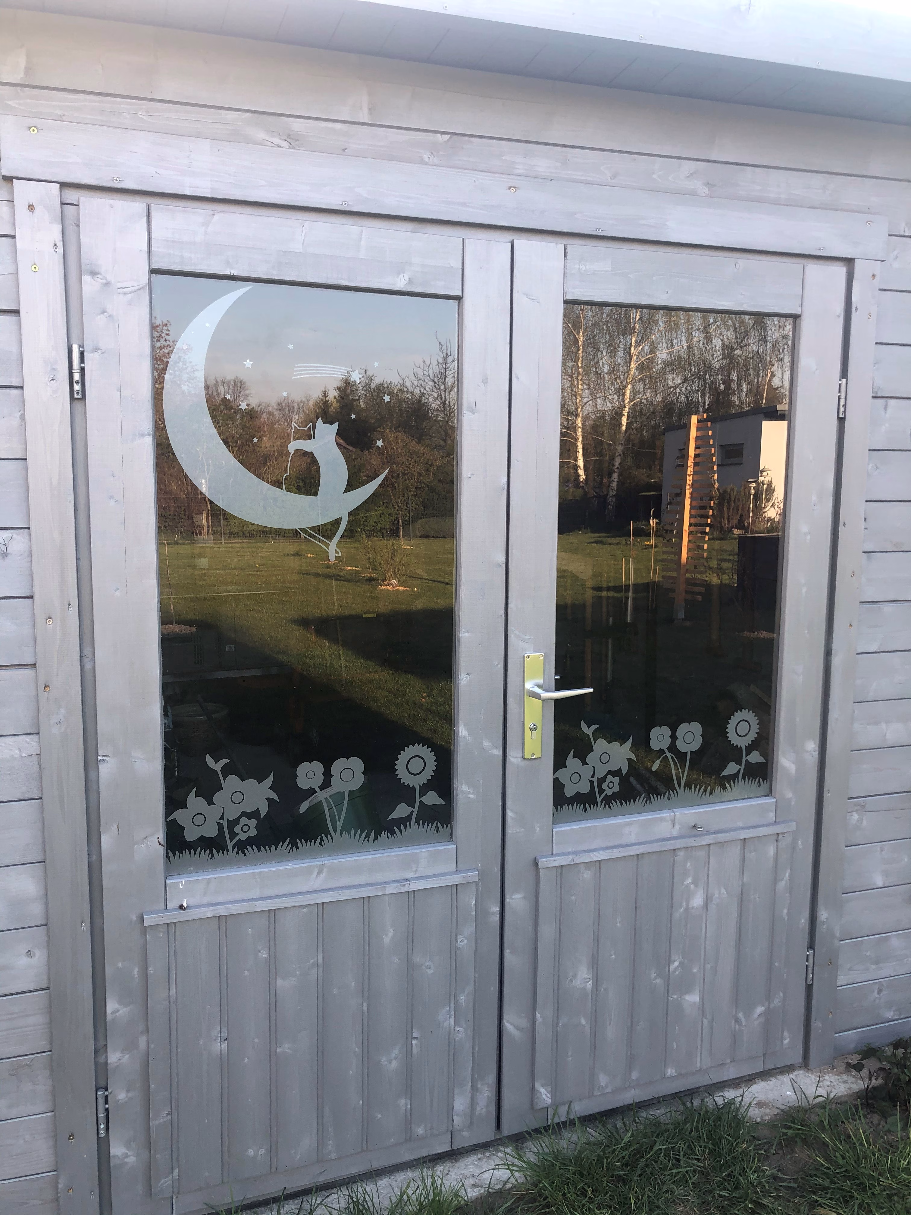 Glasdekor für Fenster mit Motiv Blumenwiese auf einem Gartenhaus