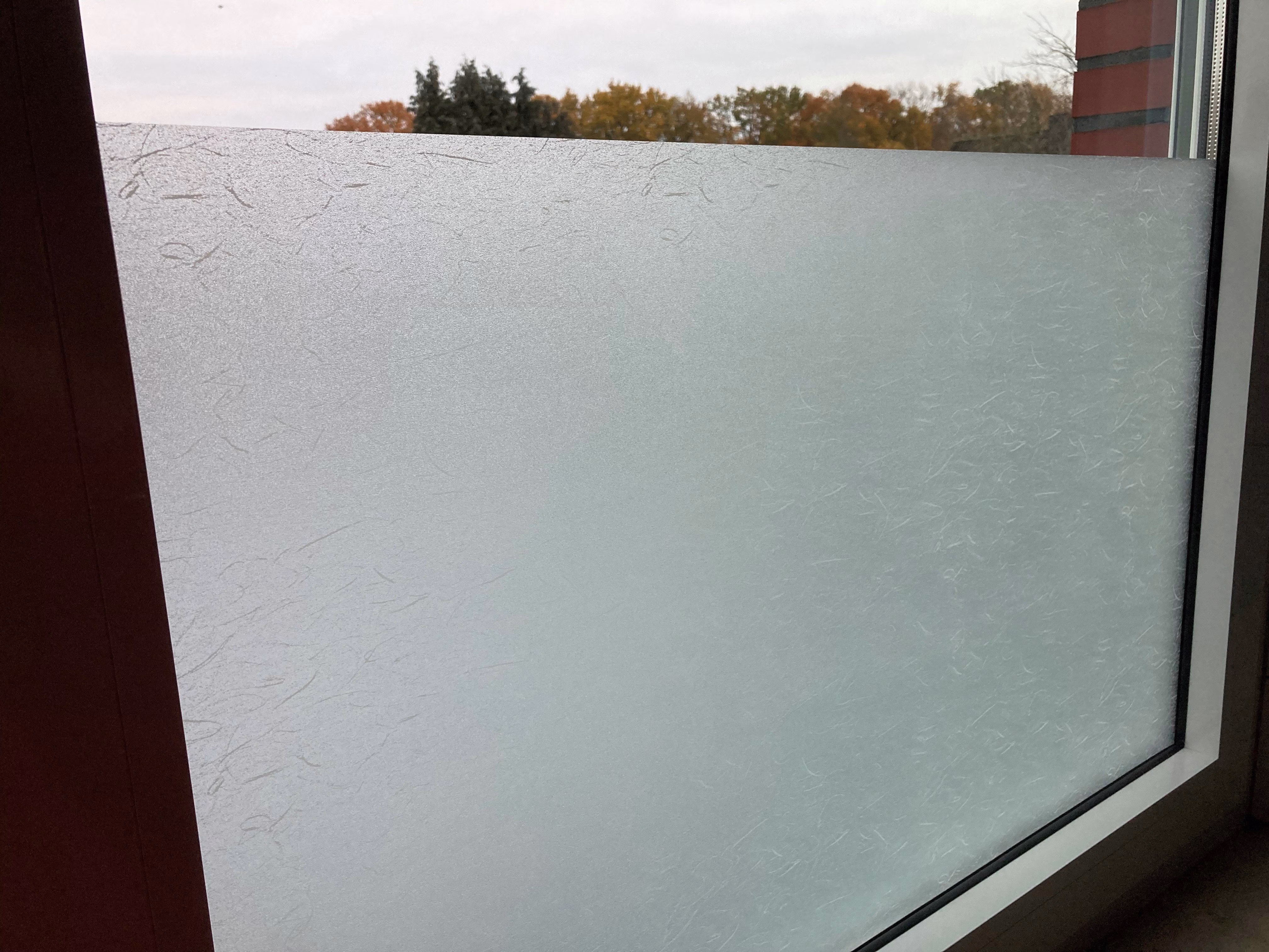 Ein Fenster welches mit selbsthaftender Folie in Faser-Optik als Sichtschutz teilbeklebt worden ist.