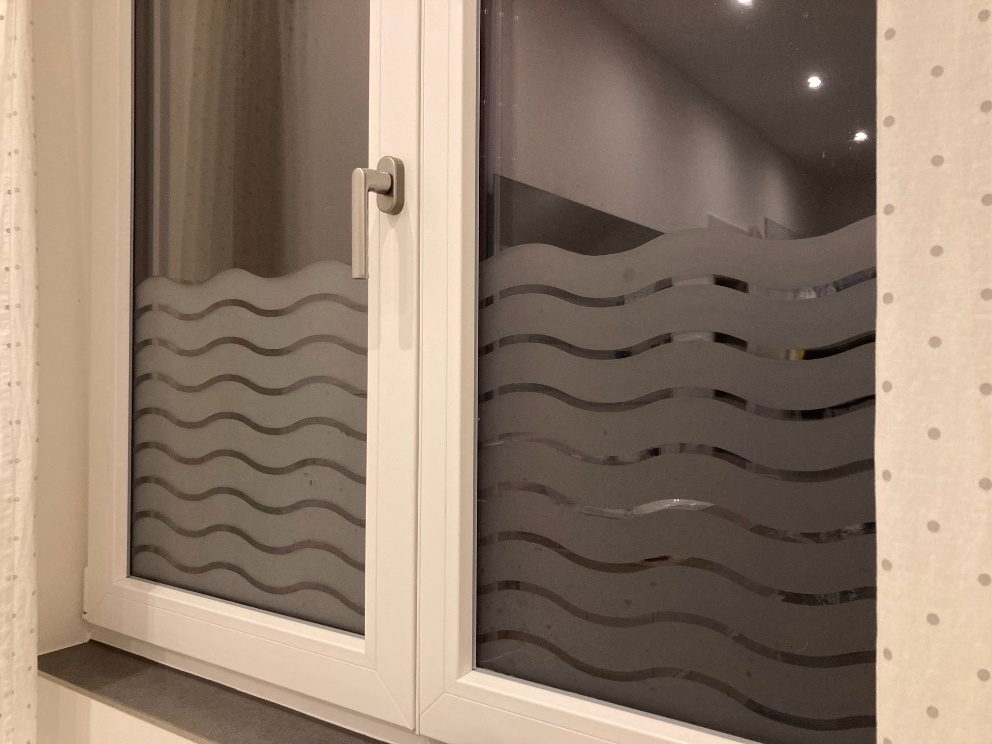 Sichtschutzfolie mit Wellenmuster auf einem Doppelfenster bei Nacht