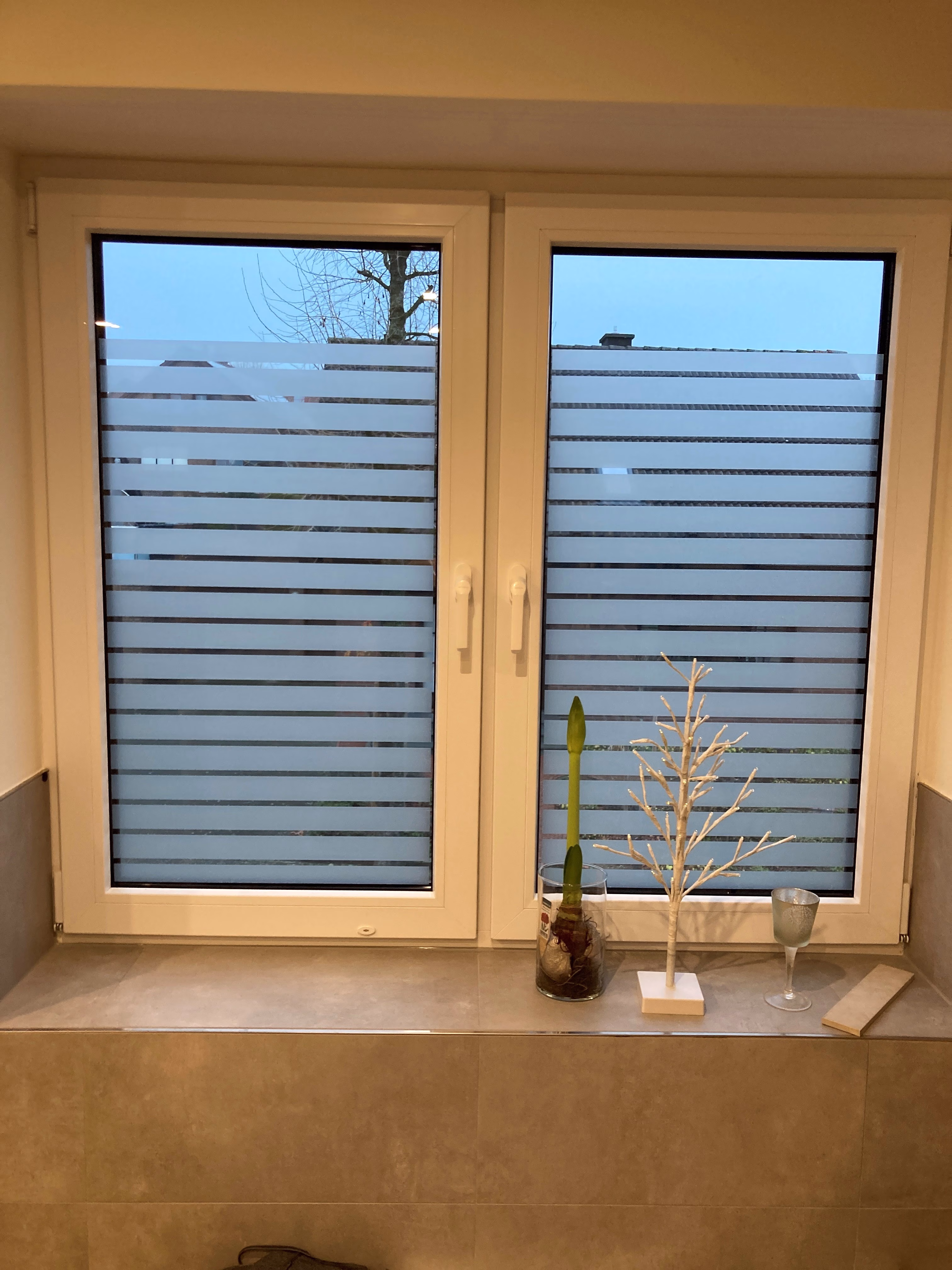 Mattierte Streifenfolie auf einem Badezimmerfenster Mattierte Streifenfolie auf einem Badezimmerfenster