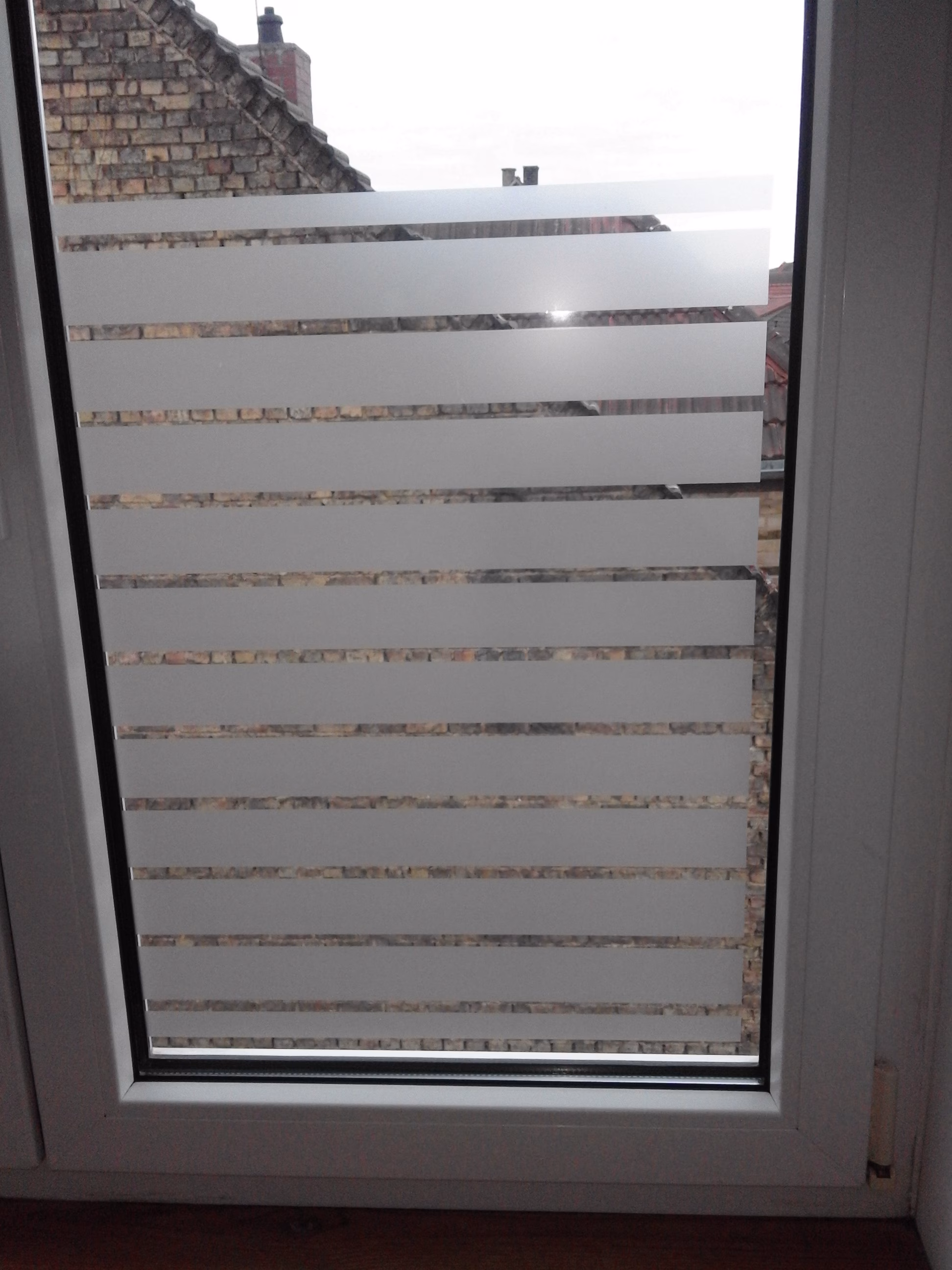 Dekorfolie mit weiß matten Streifen auf einem Fenster montiert als Sichtschutz