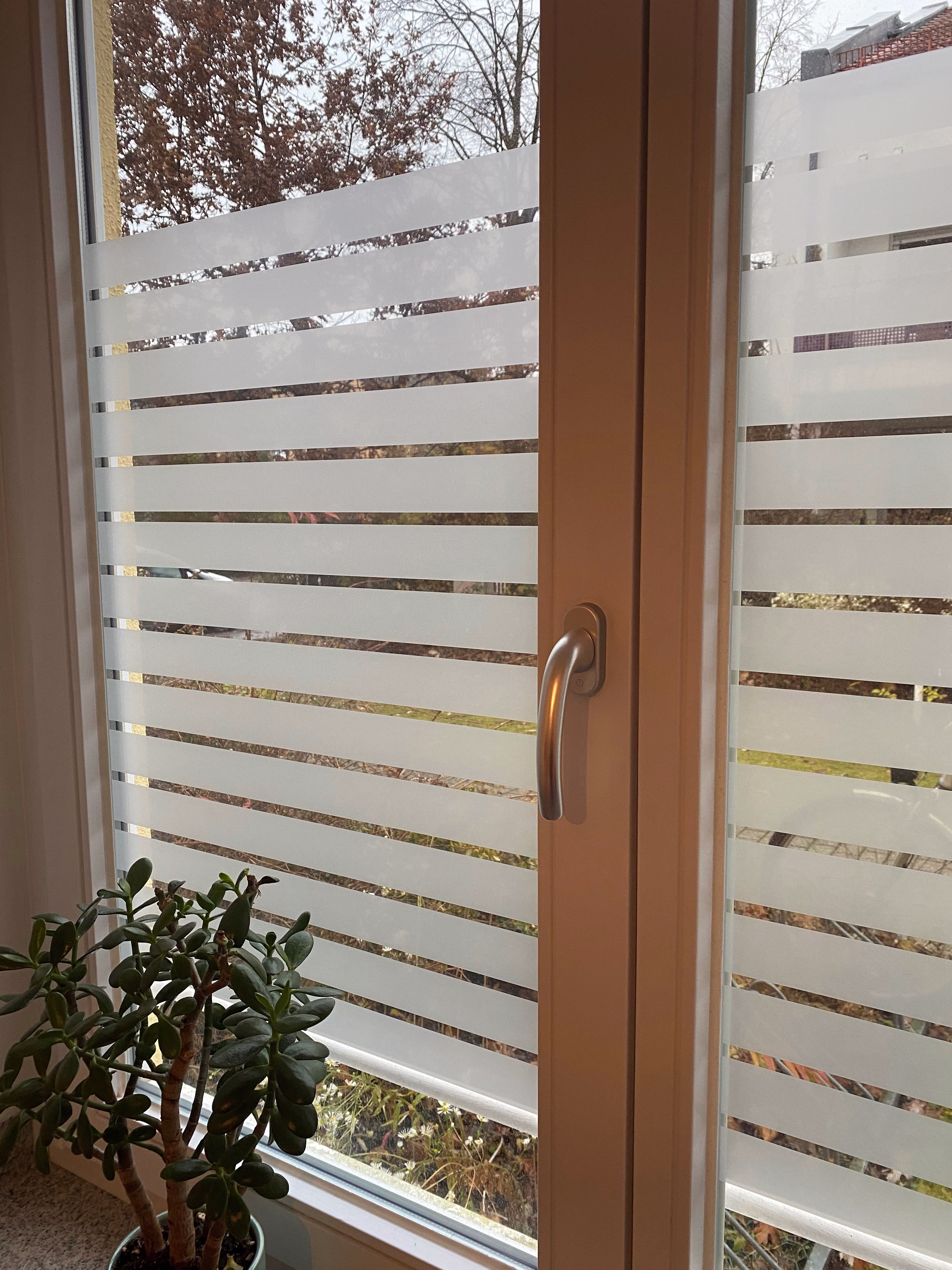 Sichtschutzfolie mit breiten weißen Streifen auf einem Fensterglas Sichtschutzfolie mit breiten weißen Streifen auf einem Fensterglas