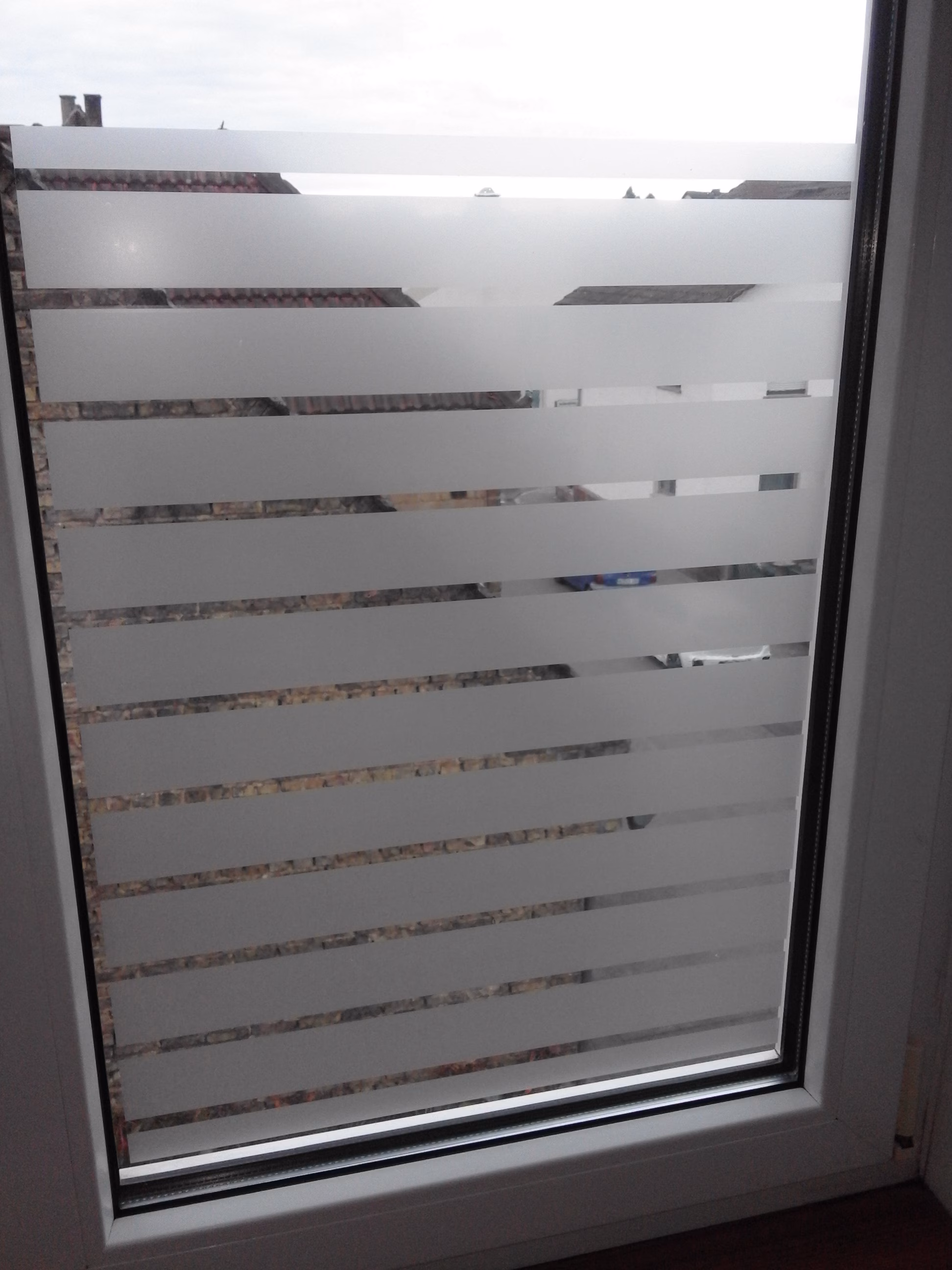 Dekorfolie mit weiß matten Streifen als Sichtschutz auf einem Fenster