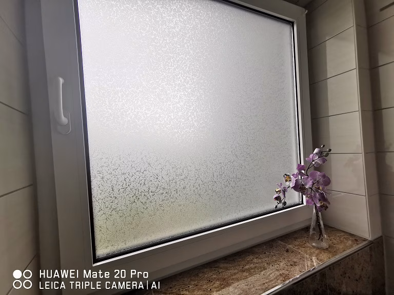 Adhäsionsfolie Frosted auf einem Badezimmerfenster angebracht.