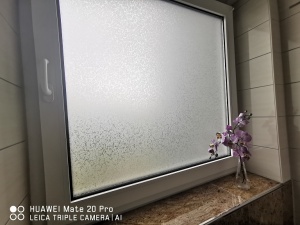 Adhäsionsfolie Frosted auf einem Badezimmerfenster angebracht.
