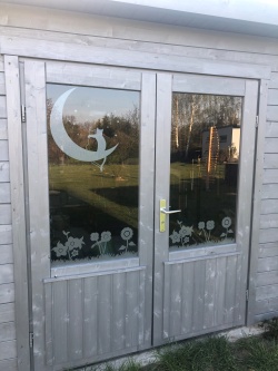 Glasdekor für Fenster mit Motiv Blumenwiese auf einem Gartenhaus