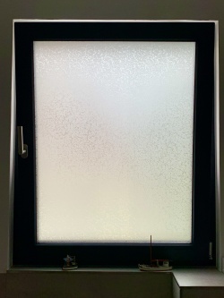 Adhäsiosfolie in Frostglasoptik auf Fensterscheibe im Bad
