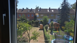 Silber hell verspiegelte Sonnenschutzfolie an einem Fenster mit Blick in den Garten